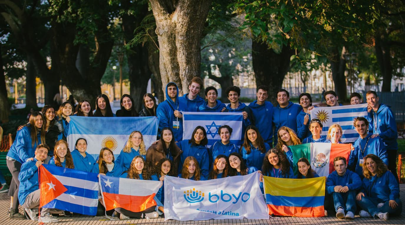 A diverse crowd of people celebrating at a concert, raising their hands and cheering.