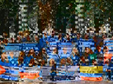 קהל מגוון של אנשים חוגג בקונצרט, מרימים את ידיהם ומריעים.