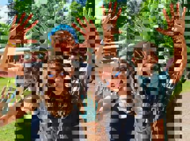 קהל מגוון של אנשים חוגג בקונצרט, מרימים את ידיהם ומריעים.