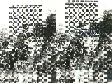 קהל מגוון של אנשים חוגג בקונצרט, מרימים את ידיהם ומריעים.