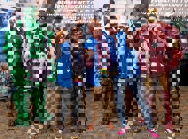 קהל מגוון של אנשים חוגג בקונצרט, מרימים את ידיהם ומריעים.