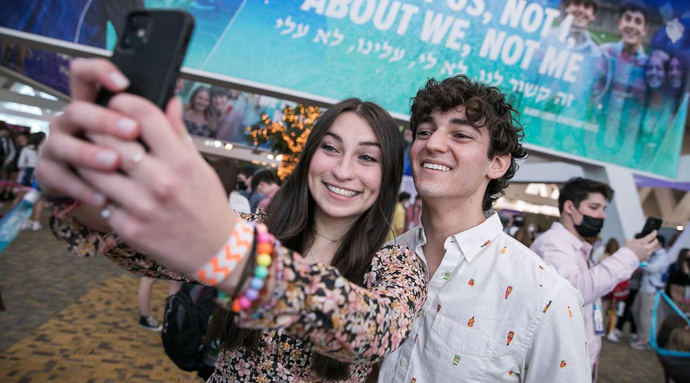 A diverse crowd of people celebrating at a concert, raising their hands and cheering.