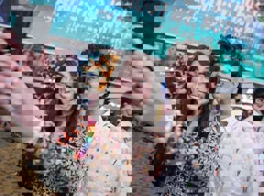 קהל מגוון של אנשים חוגג בקונצרט, מרימים את ידיהם ומריעים.